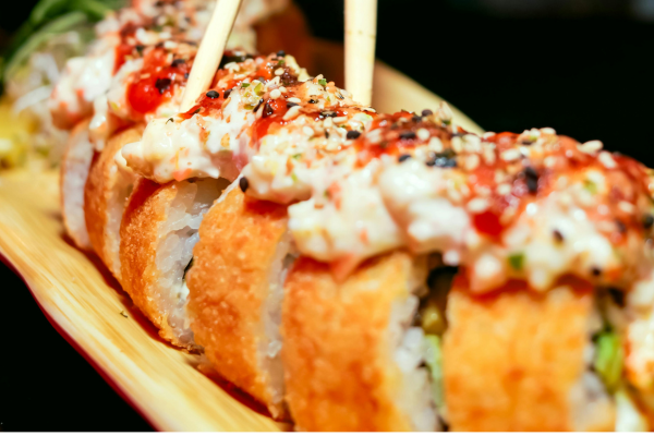 Cenital limpio de uramaki con salmón/aguacate y toques de mango, más tartar de salmón con mango en plato auxiliar; paleta rosa-verde fresca en el menu Infinity