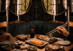 Imagen principal del blog con una mesa de Sushisom preparada con sushi, gyozas, edamame y platos calientes en un ambiente cálido de restaurante japonés. Refuerza la idea de disfrutar el Menú Infinity en septiembre con una mesa ordenada, variedad y una exp
